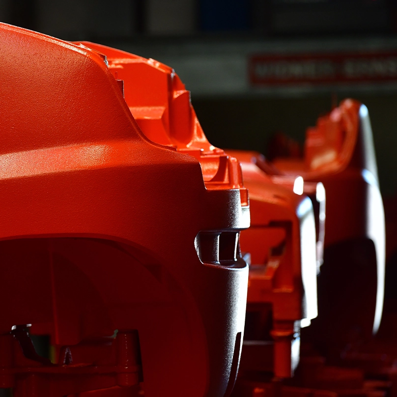 Close-up of several red-painted forklift counterweights lined up in a row.